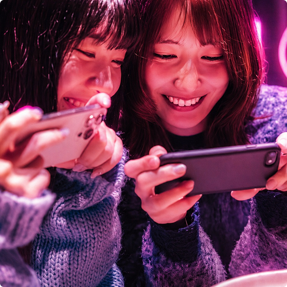 スマートフォンを見ながら笑い合う女性たち